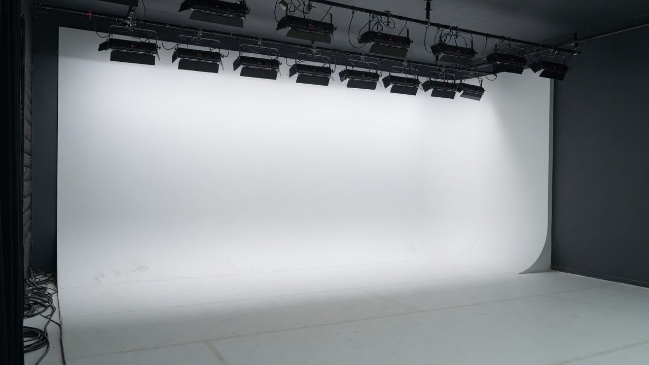 Empty white cyclorama studio, lights on a rail, cyc curve meeting the floor.
